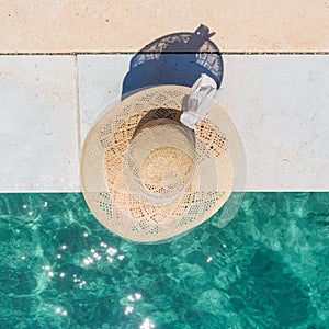 Woman wearing big summer sun hat relaxing on pier by clear turquoise sea.