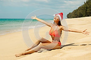 Woman wearing bikini and Christmas hat on the beach. Winter holidays in the warm countries.