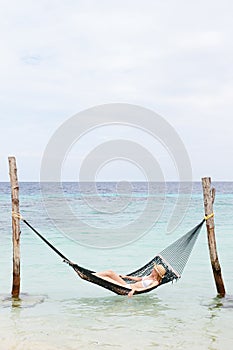 Woman Wearing Bikini And Sun Hat In Beach Hammock