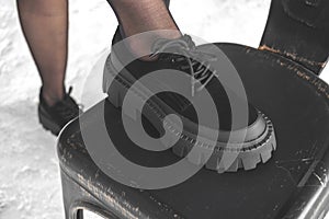 Woman wearing black boots close-up view, concrete background, urban street fashion concept