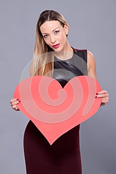 Woman wearing black dress holding big heart sign love symbol