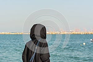 A woman wearing black hijab looking at the sea at the corniche park in Dammam, Kingdom of Saudi Arabia photo