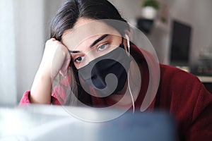 A woman wearing a black mask trying to stay focused while working from home due to Covid-19, struggling with anxiety and depressio