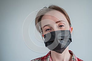 Woman wearing black medical face mask, looking at camera - quarantine concept