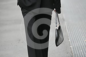 Woman wearing black pants, coat and handbag