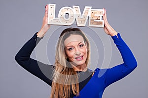 Woman wearing blue dress holding sign love symbol