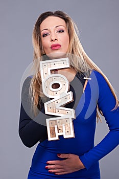 Woman wearing blue dress holding sign love symbol