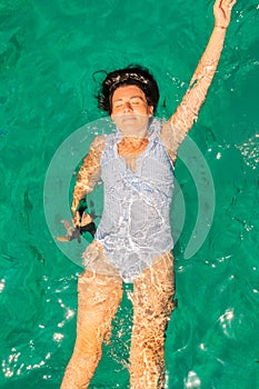 Woman wearing blue white swimsuit relaxing in the sea enjoying summer in Zakynthos island in Greece. Top view.