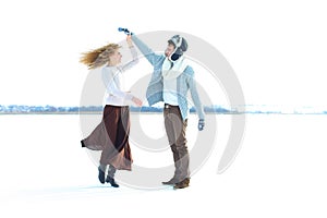 Woman wearing brown skirt and sweater dancing with man in snow background.