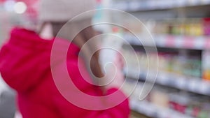 Woman wearing in a busy hypermarket, browsing products and making a purchase.