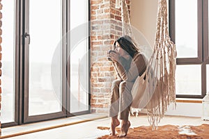 Woman wearing cashmere nightwear relaxing in cabin near fireplace