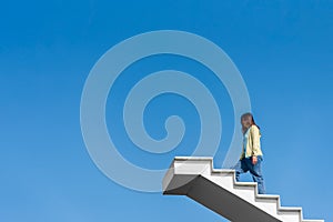 Woman wearing casual dress walking up the white stairs felling hopeful, energized, carefree, tranquil and successful in a