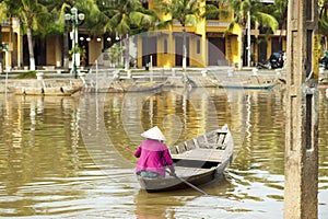 Woman wearing conical hat rowing the boat at Hoi An