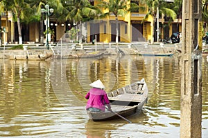 Woman wearing conical hat rowing the boat at Hoi An photo