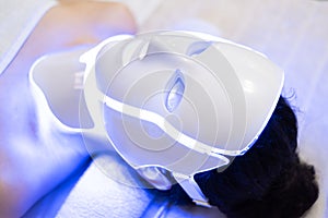 Woman is wearing cosmetic face photon mask. Health and beauty. Cosmetic procedure for woman face. Beauty laboratory. LED Facial