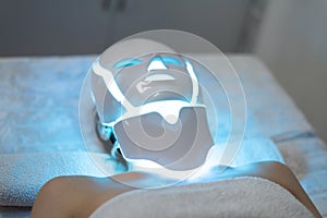 Woman is wearing cosmetic face photon mask. Health and beauty. Cosmetic procedure for woman face. Beauty laboratory. LED Facial