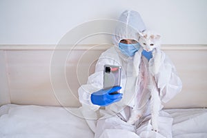 Woman wearing in coverall and talking on video communication on smartphone and holding cat