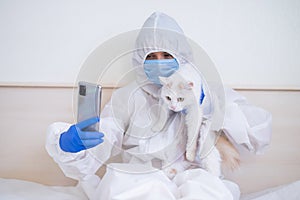 Woman wearing in coverall and talking on video communication on smartphone and holding cat