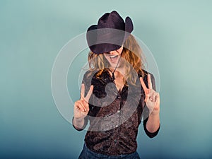 Woman wearing cowboy hat showing peace sign