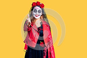 Woman wearing day of the dead costume over background smiling friendly offering handshake as greeting and welcoming