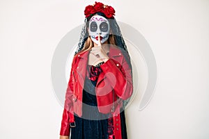 Woman wearing day of the dead costume over white asking to be quiet with finger on lips