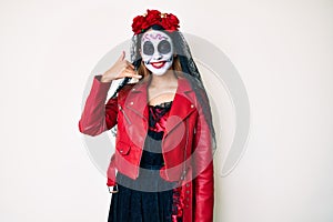 Woman wearing day of the dead costume over white smiling doing phone gesture with hand and fingers like talking on the telephone