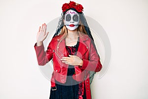 Woman wearing day of the dead costume over white swearing with hand on chest and open palm, making a loyalty promise oath