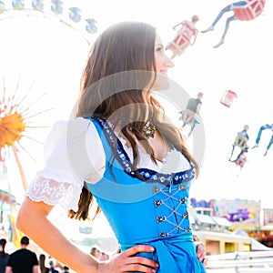 Woman wearing dirndl standing in front of ferris wheel