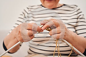 Woman wearing domestic clothes holding knitting needles while knitting