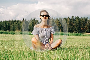 Woman wearing dress sitting on green grass field