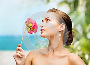 Woman wearing earrings and smelling flower