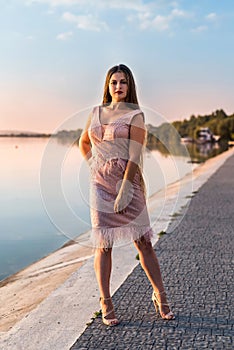 Woman wearing evening peach color gown against lake