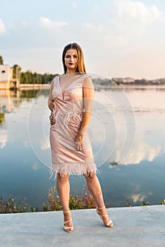 Woman wearing evening peach color gown against lake