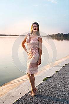 Woman wearing evening peach color gown against lake