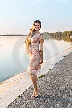 Woman wearing evening peach color gown against lake