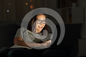 Woman wearing eyeglasses using a laptop in the night