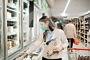 Woman wearing face mask buying in supermarket.Panic shopping during Coronavirus covid-19 pandemic.Budget buying at a supply store.