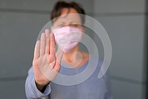 Woman wearing a face mask giving a Halt gesture