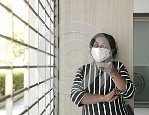 Woman wearing face mask leaving voice message on her cellphone