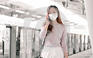 Woman wearing face mask and talking on mobile phone while standing on railway station