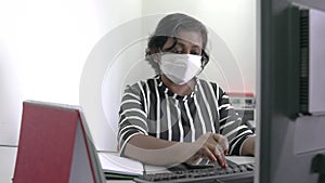 Woman wearing face mask typing on her computer keyboard.