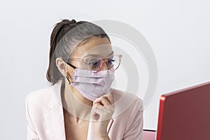 Woman wearing a face mask using a computer and working from home.