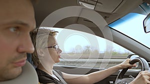 Woman wearing glasses while driving a car, the man in the passenger seat