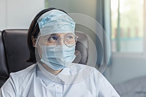 A woman wearing glasses and two masks is in the room worried