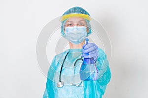 Woman wearing gloves, biohazard protective suit, face shield and mask with hand sanitizer bottle and disinfection gel. corona