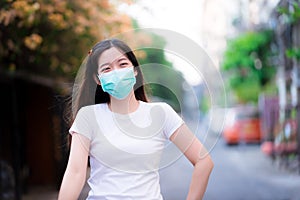 Woman wearing a green surgical face mask is walking on public roads. People smile sweetly through their eyes  under medical masks
