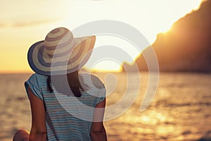 Woman wearing hat admire the sunset over the sea