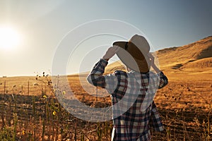 Woman wearing hat from behind looking at view of rural california landscape