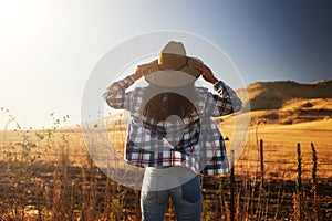 Woman wearing hat from behind looking at view of rural california landscape