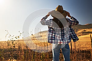 Woman wearing hat from behind looking at view of rural california landscape